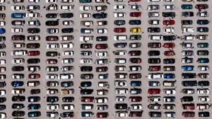 Top-down aerial shot of a large parking lot filled with rows of cars, showcasing organized symmetry.